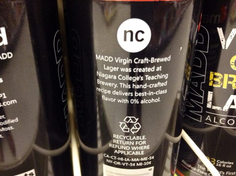 Close-up of several cans of MADD Virgin Craft-Brewed Lager with text describing it as a hand-crafted non-alcoholic beer created at Niagara College's Teaching Brewery.