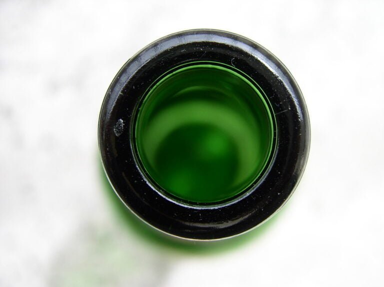 Top-down view of a bottle with green liquid, highlighting the bottle's rim and the liquid's surface tension.