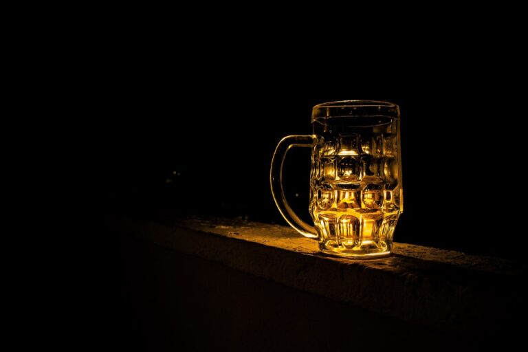 An illuminated beer mug on a ledge against a dark background.