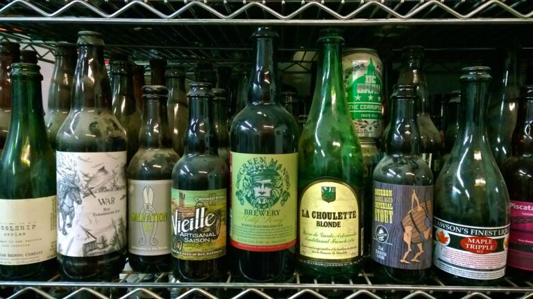 A variety of craft beer bottles with distinct labels on a metal rack.