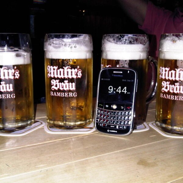 Three pint glasses of beer with the logo "Mahrs Bräu Bamberg" on them and a Blackberry smartphone showing the time as 9:44 are placed on a wooden surface.