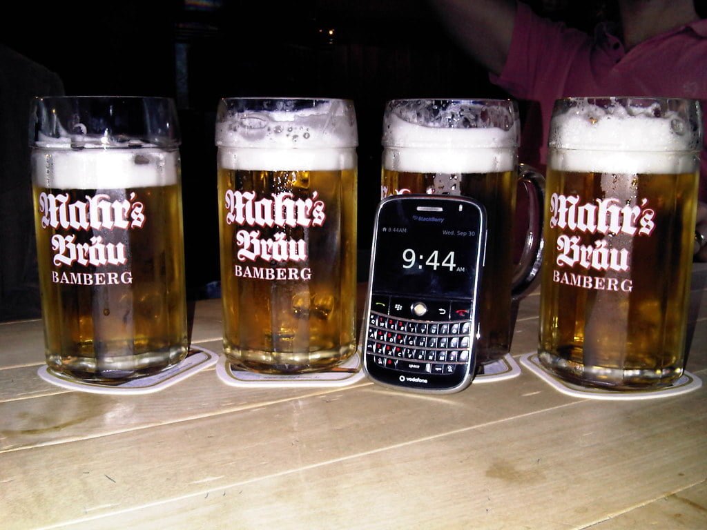 Three pint glasses of beer with the logo "Mahrs Bräu Bamberg" on them and a Blackberry smartphone showing the time as 9:44 are placed on a wooden surface.