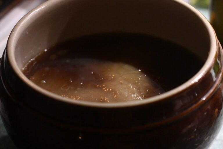 A close-up of a brown ceramic bowl, with steam rising from the surface.