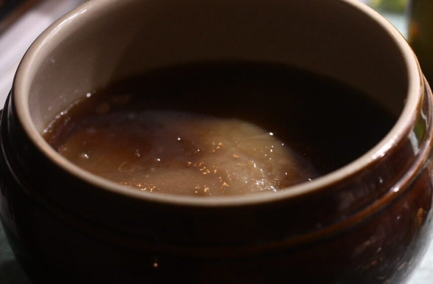 A close-up of a brown ceramic bowl, with steam rising from the surface.
