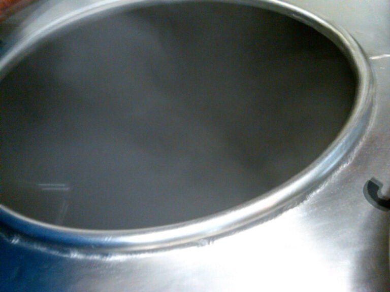 A large pot of boiling water with steam obscuring the contents.