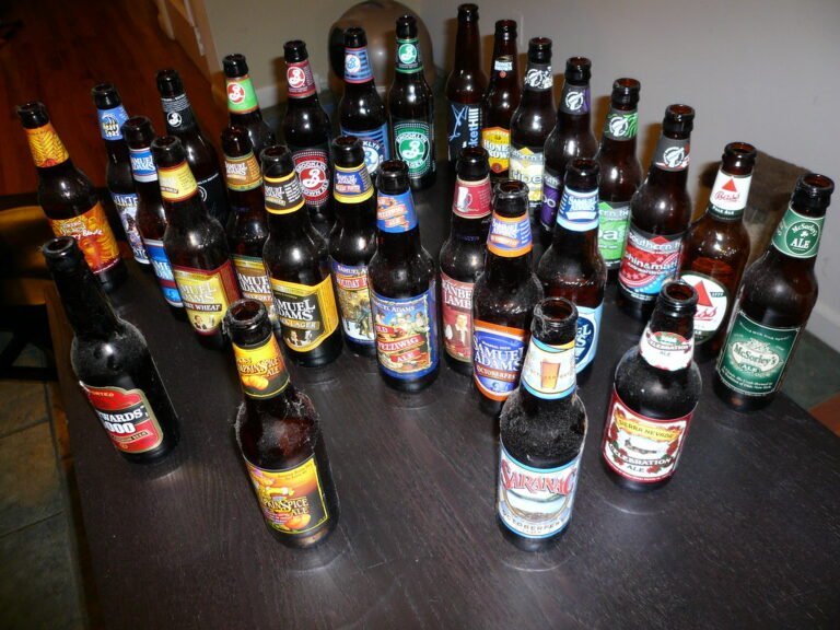A collection of various empty beer bottles arranged on a wooden surface.