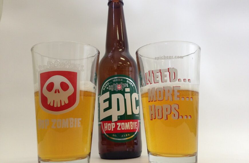 Two pint glasses of beer with different logos ("HOP ZOMBIE" on the left, "NEED... MORE... HOPS..." on the right) flanking a central beer bottle labeled "Epic HOP ZOMBIE" against a white background.