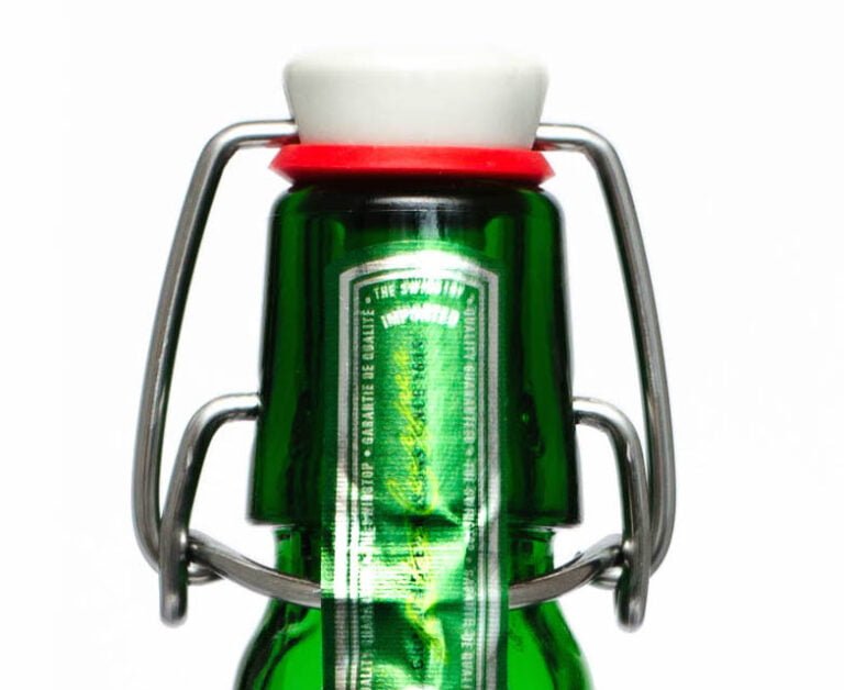 Close-up of a green glass bottle with a flip-top cap and metal clasp, isolated on a white background.