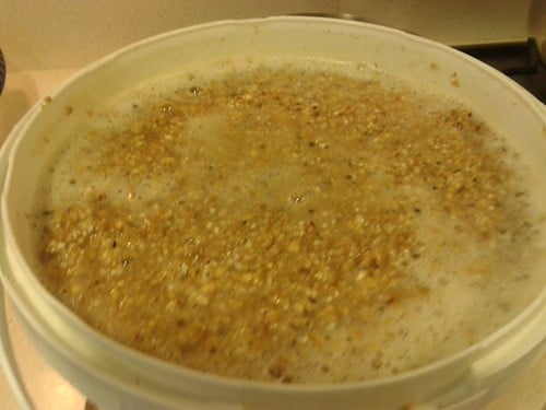 A pot of boiling grains on a stove with steam rising from the surface.