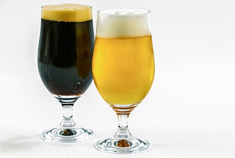 Two glasses of beer with frothy heads on a white background, one filled with dark beer and the other with light beer.