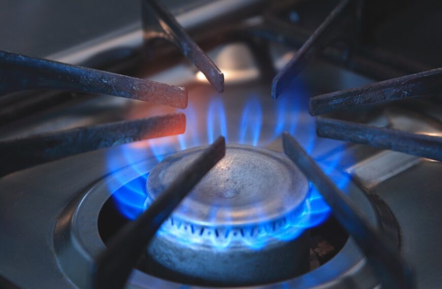 A close-up image of a gas stove burner with a blue flame.