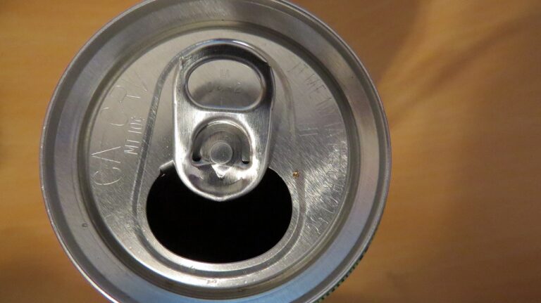 Close-up of an opened aluminum beverage can top with a pull tab, showing engraved text on the silver surface and a dark hollow inside the can.