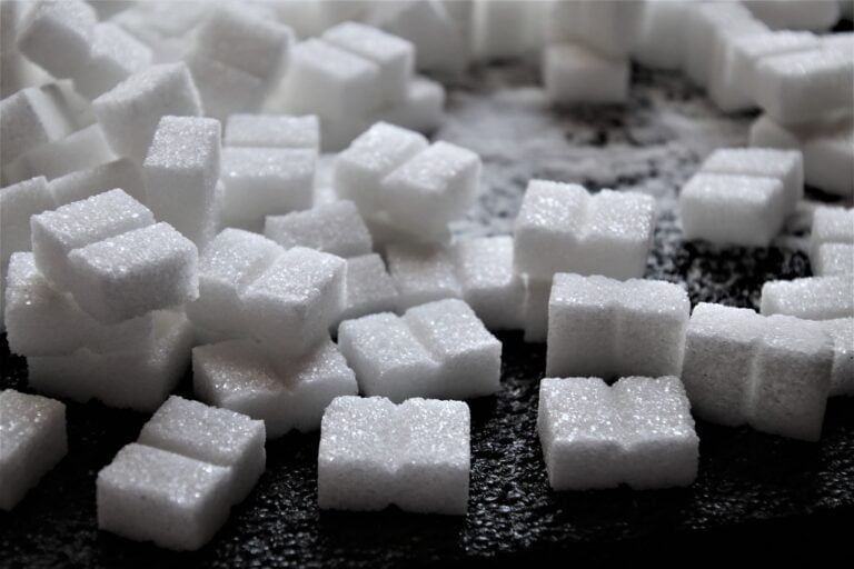 Close-up of multiple white sugar cubes scattered on a dark surface.