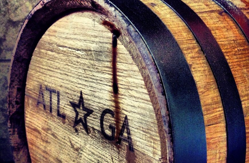 A close-up of a wooden barrel with the inscription "ATL GA" and a star, showing signs of liquid seepage.