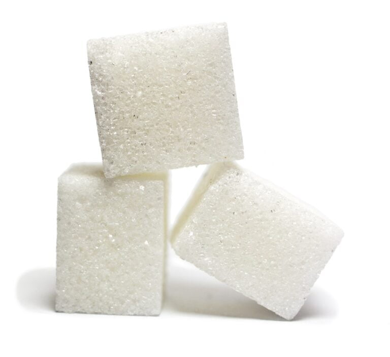 Three white sugar cubes stacked irregularly against a white background.